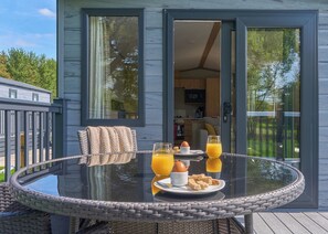 A dining table with breakfast items and a glass of orange juice on a deck. - Luxury 3 bedroom Hot Tub sleeps 8 Pet Friendly (Hayle)