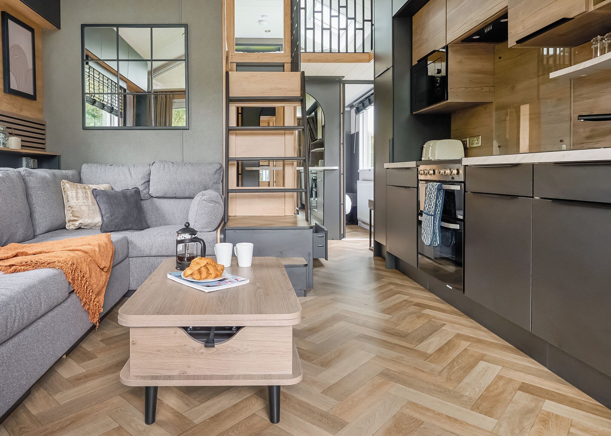 A modern living space with a sofa, coffee table, and kitchen area.