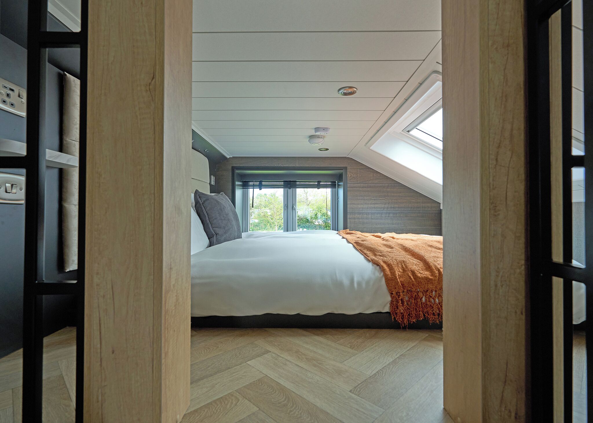 A bedroom with a bed, a window, and a skylight.