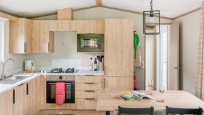 Una cocina moderna con armarios de madera, horno empotrado y zona de comedor con mesa y sillas.