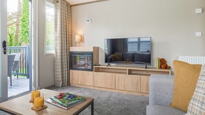 Una sala de estar con televisión, sofá, mesa de centro y vistas al exterior.