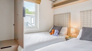 Habitación de hotel con dos camas, una ventana con vistas, una mesita de noche con lámpara y un armario.