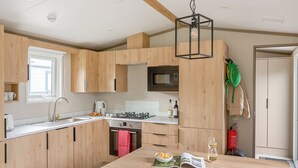 Una cocina moderna con armarios de madera, estufa a gas, microondas y un comedor con mesa y sillas.
