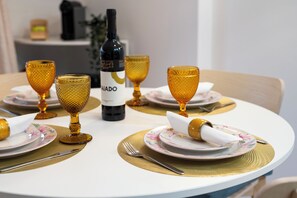 A dining table set with golden glassware, plates, and a bottle of wine. - Refurbished apartment in private condominium with pool in Vilamoura Marina (Quarteira)