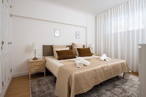 A neatly arranged bedroom with a bed, bedside tables, and a large window with sheer curtains. - Refurbished apartment in private condominium with pool in Vilamoura Marina (Quarteira)