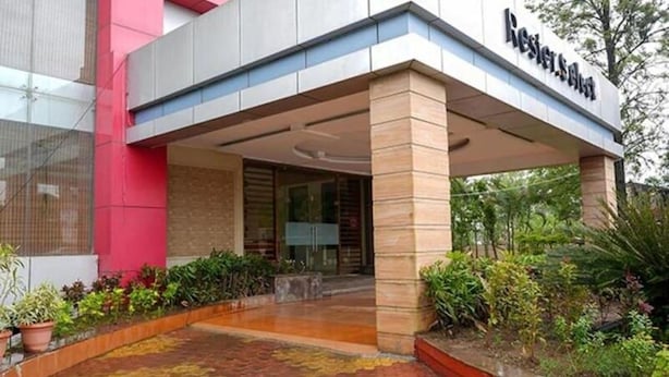 A hotel entrance with a covered walkway, a name sign, and surrounding greenery. - Rester Select Chakan (Rajgurunagar)