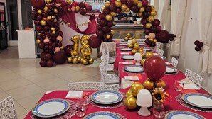 Ein Banketthaus mit festlich gedeckten Tischen, ein Ballonbogen im Zentrum und ein Kronleuchter.