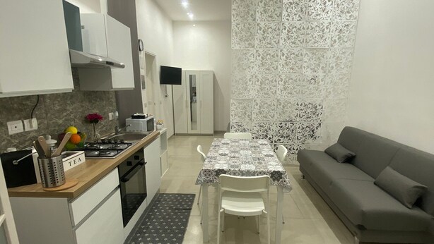Een moderne keuken met witte kasten, een gasfornuis en een eethoek met een tafel en stoelen.