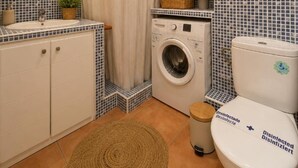 Un bagno compatto con lavatrice, toilette e specchio.