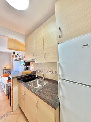 Eine moderne Küche mit hellen Holzschränken, einer Edelstahlspüle und einem Zanussi-Kühlschrank.