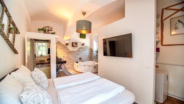 Een slaapkamer met een groot bed, een stenen muur, een open haard en een aan de muur bevestigde televisie.