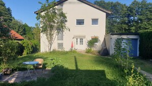 A two-story house with a white exterior, a small front yard, and a blue door. - Cozy garden apartment near Herrsching (Herrsching am Ammersee)