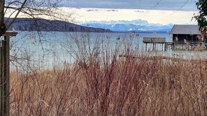 A lakeside view with a wooden dock and a cabin in the background. - Cozy garden apartment near Herrsching (Herrsching am Ammersee)