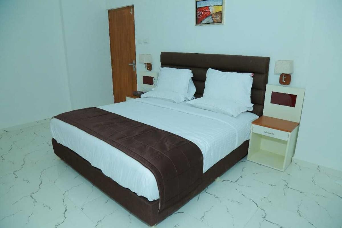 Ein Schlafzimmer mit einem großen Bett, zwei Nachttischen, einem Wanduhr und einer Tür.