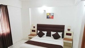 Hotelkamer met een bed, twee nachtkastjes, een wanddecoratie en een raam met gordijnen.