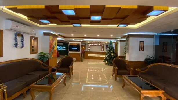 Een hotel lobby met een receptiebalie, kerstboom en een zithoek met banken en salontafels.