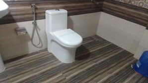 Een badkamer met toilet, douche en een vloer met een patroon.