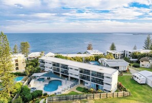 A modern multi-story building with a swimming pool and a view of the sea. - Pacific View has Spa Sauna Pool table tennis & is Non Smoking Accommodation. (Kings Beach)