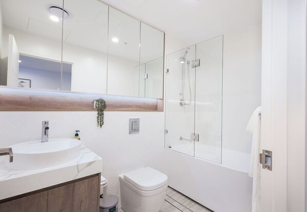 Une salle de bain moderne avec un lavabo rond, des toilettes et une douche à parois de verre.
