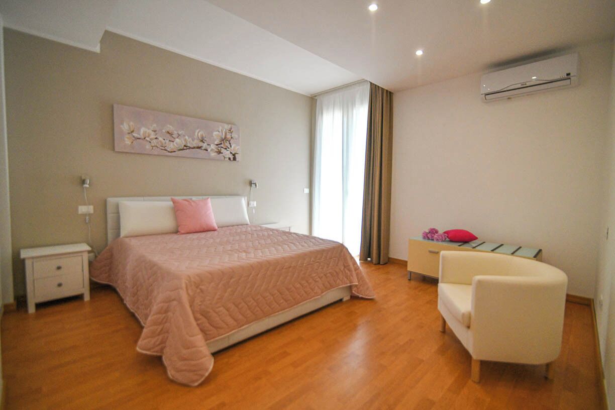 A bedroom with a bed, bedside tables, a chair, and a painting on the wall.