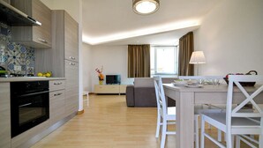Una cocina moderna con comedor, suelo de madera y vista al salón.