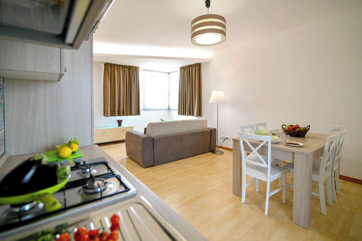 Eine moderne Küche mit Gasherd, ein Essbereich mit Tisch und Stühlen, ein Sofa und eine Lampe.