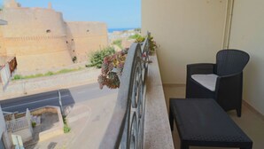 Ein Balkon mit Stuhl und Tisch, mit Blick auf eine Straße und ein historisches Gebäude.