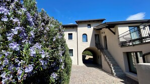 A building with a stone archway, a staircase, and a balcony with a railing. - Villetta Moscal- „BuonGusto“ (Affi)