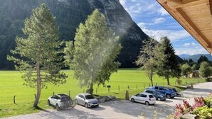 A parking area with cars, a mountain backdrop, and a wooden structure. - Mountain View Deluxe: enjoy mountain views together, a balcony, and alpine luxury. Perfect for a romantic stay in summer or winter. (Leutasch)