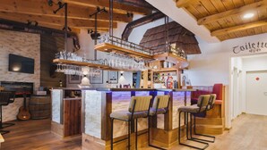 A bar area with stools, a counter, and a hanging glass rack. - Mountain View Deluxe: enjoy mountain views together, a balcony, and alpine luxury. Perfect for a romantic stay in summer or winter. (Leutasch)