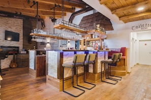 A bar area with stools, a counter, and a hanging glass rack.