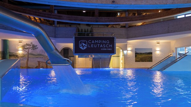 A swimming pool with a water slide, a sign for Camping Leutasch, and a mountainous landscape view. - Mountain View Deluxe: enjoy mountain views together, a balcony, and alpine luxury. Perfect for a romantic stay in summer or winter. (Leutasch)