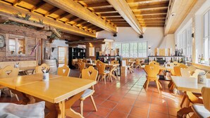 A restaurant with wooden tables and chairs, a brick wall, and a high wooden ceiling. - Relax in the Premium Room of Leutasch Retreat: extra space, bath and shower, ideal for active summers and winters in Tyrol. (Leutasch)