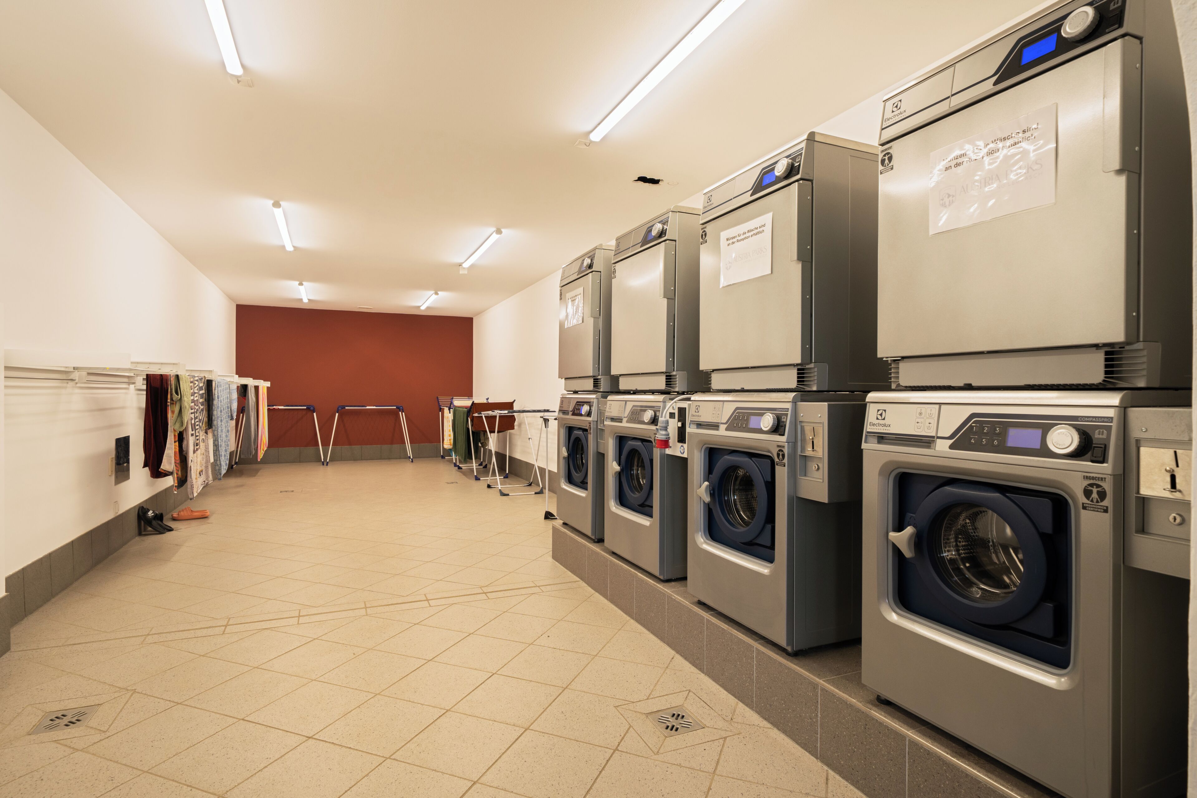 A laundry facility with multiple washing machines, a drying rack, and a folding station.
