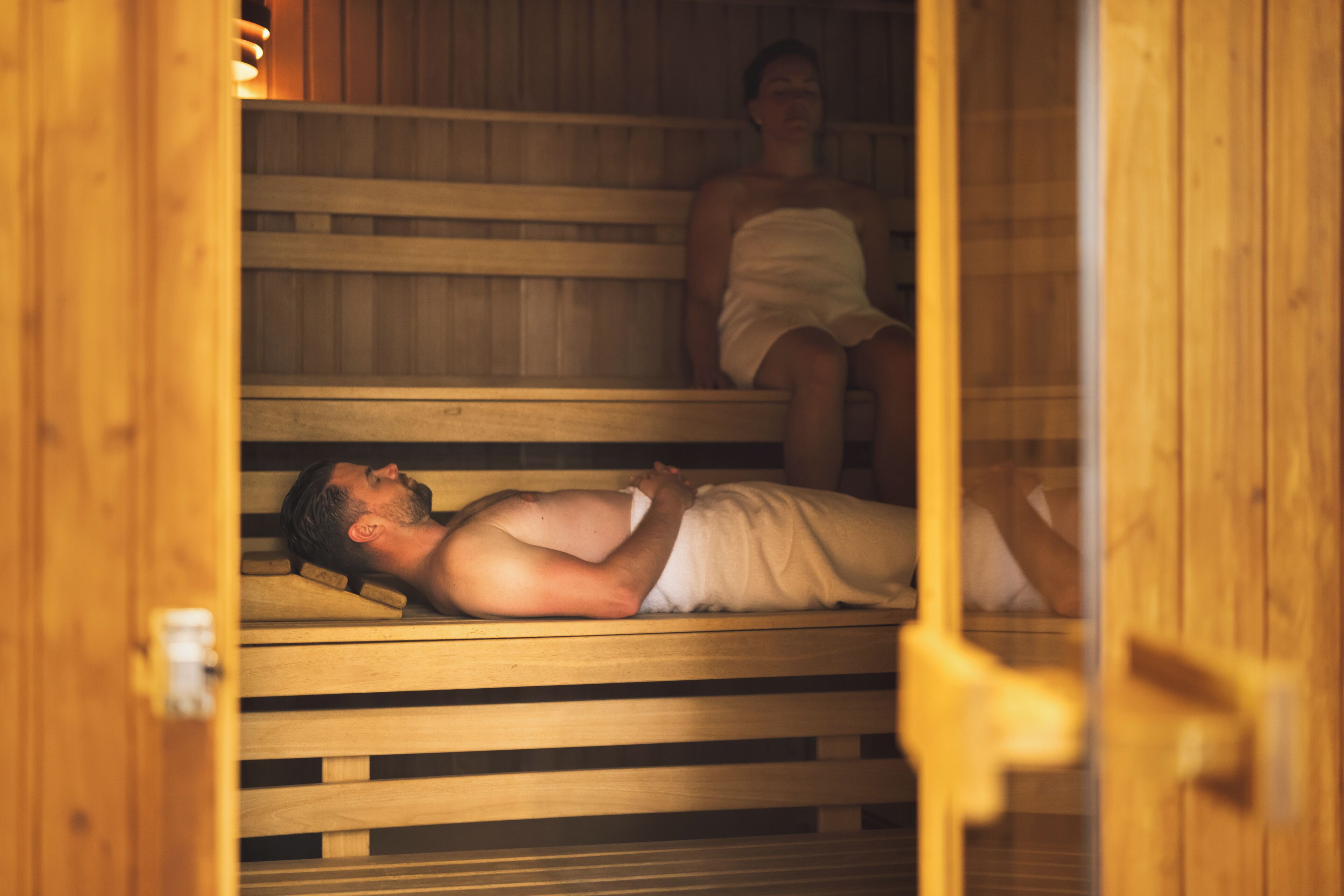 Un sauna avec des bancs en bois et une personne allongée.