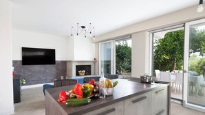 A modern kitchen with a large island, a flat-screen TV, and a glass door leading to an outdoor area. - Sorrento Sea View Villa - 4BR, Panoramic Terraces & Private Parking (Priora)