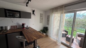 A modern kitchen with a wooden countertop, a coffee machine, and a dining area with a view of the outdoors.