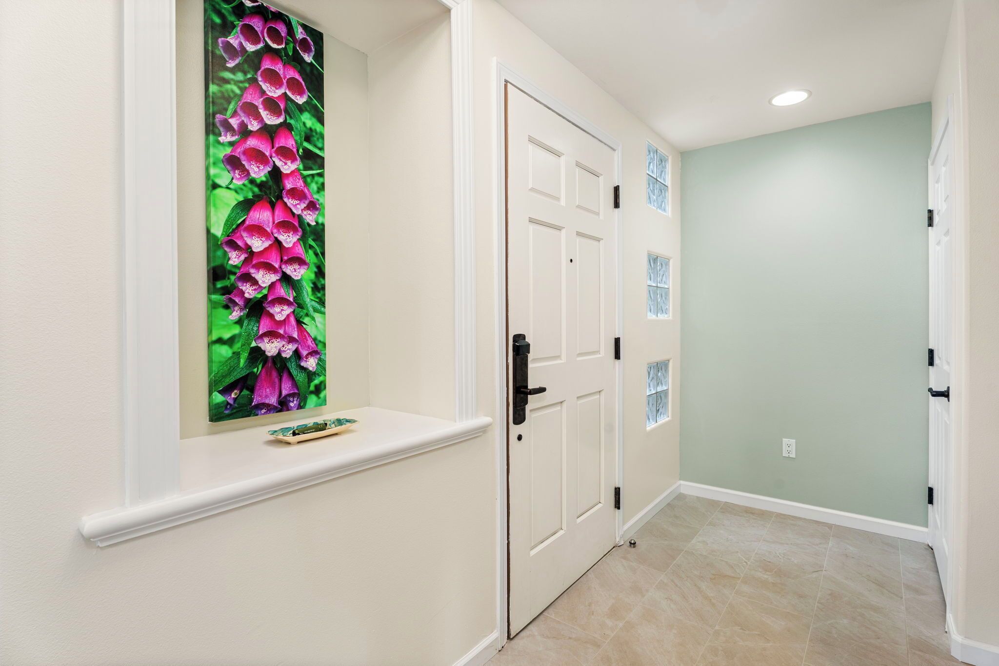 A hallway with a door, a window with a floral decoration, and a light green wall.
