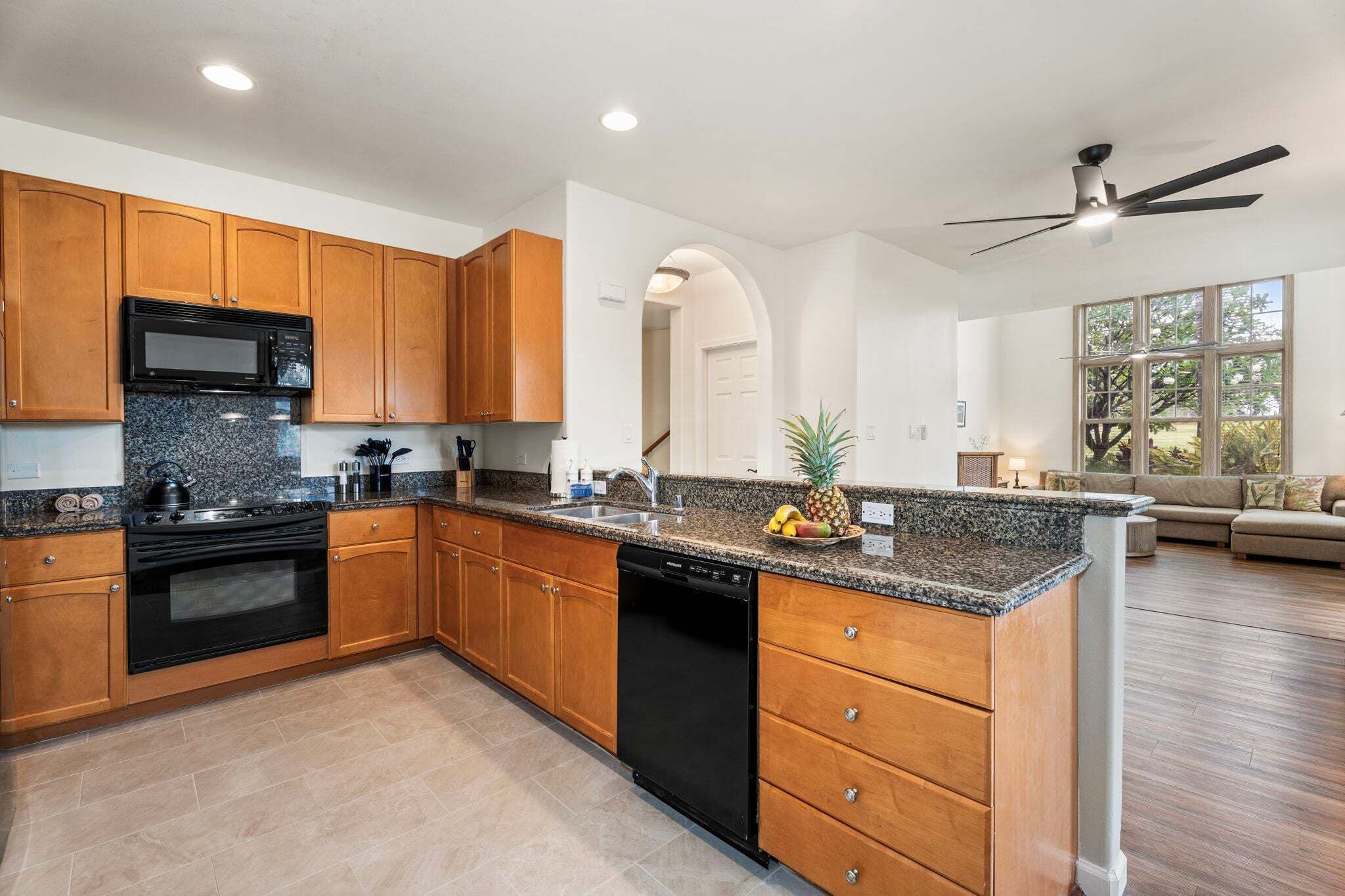 A kitchen with wooden cabinets, a black microwave, and a dishwasher.