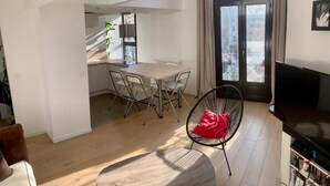 Ein modernes Wohnzimmer mit Essbereich, Fernseher und Bücherregal.