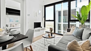 Ein modernes Wohnzimmer mit Essbereich, großen Fenstern und Blick auf die Stadt.