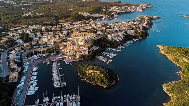 Vue aérienne d’une ville côtière avec un port de plaisance, des maisons et des bateaux.