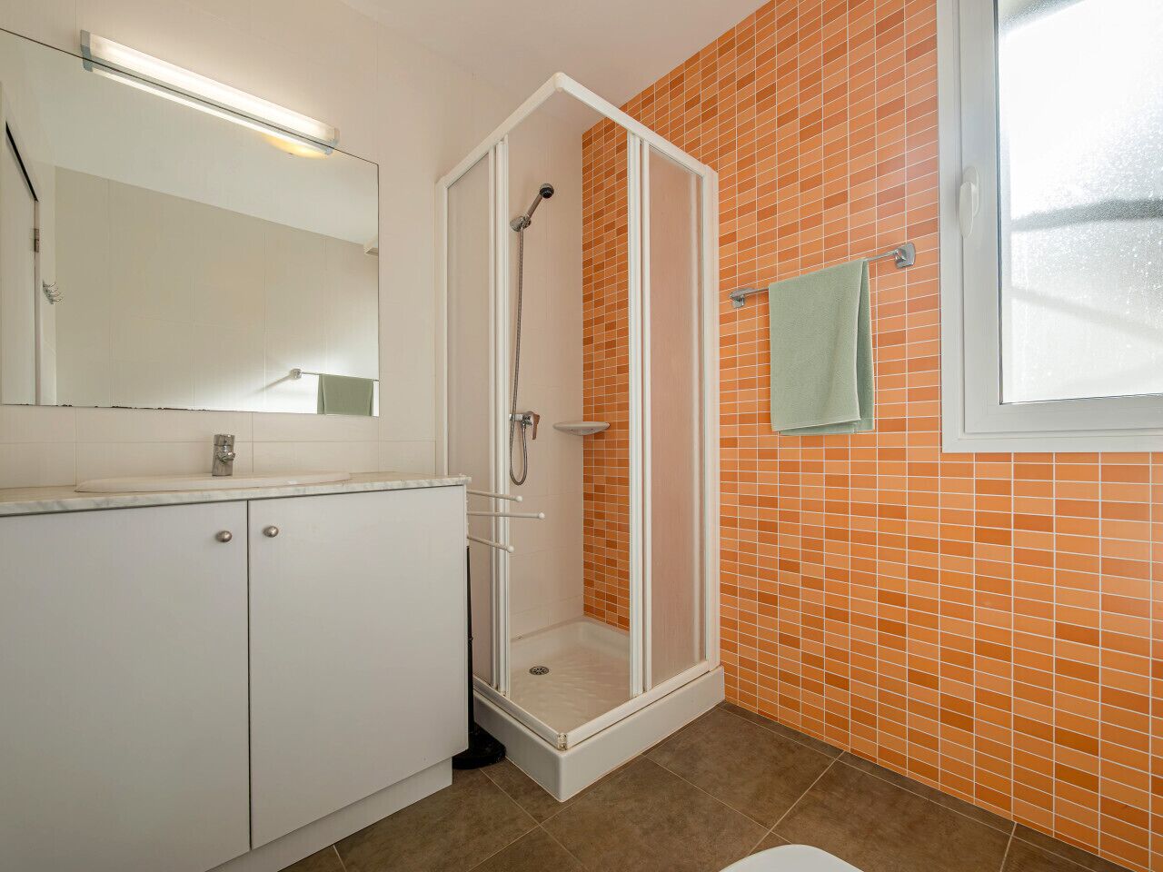 Ein Badezimmer mit Dusche, Waschbecken und Spiegel.