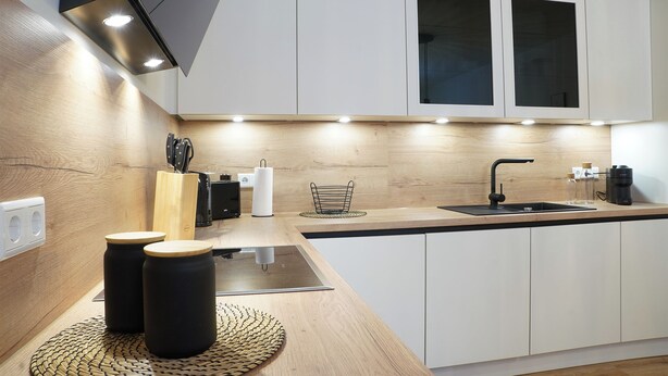A modern kitchen with white cabinets, a wooden countertop, and a black faucet. - Küste33/8 - North Sea time on the dyke. Sauna. Beach chair. Balcony. (Tossens)