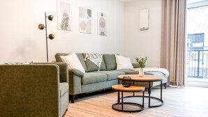 Un salon moderne avec un canapé d’angle, une table basse ronde et un lampadaire.