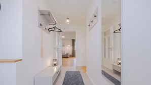 A hallway with a grey carpet, white walls, and a door leading to a room with a grey sofa. - Villa Schlossallee Rügen - thatch on the golf course. Sauna. Sea view. (Lohme)