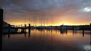 A marina at sunset with multiple boats docked and masts visible. - Villa Schlossallee Rügen - thatch on the golf course. Sauna. Sea view. (Lohme)