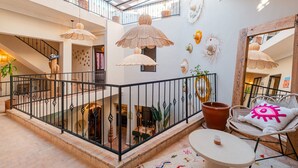 A spacious interior with a glass ceiling, a staircase, and a seating area with a round table and wicker chairs. - Riad Privé 4 Suites avec Piscine Chauffée, Rooftop & Vue Atlas – Médina (Marrakesh)