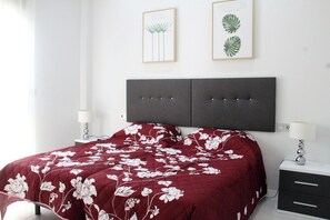 Un dormitorio con cama, dos mesitas de noche y dos lámparas de pared.