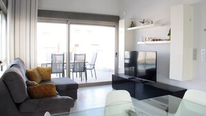 A modern living room with a sofa, a glass coffee table, a flat-screen TV, and a dining area with chairs and a table. - 5 Bed 4 Bath Villa, Private Pool, Modern, All Amenities, Pau26 Villamartin (Orihuela)